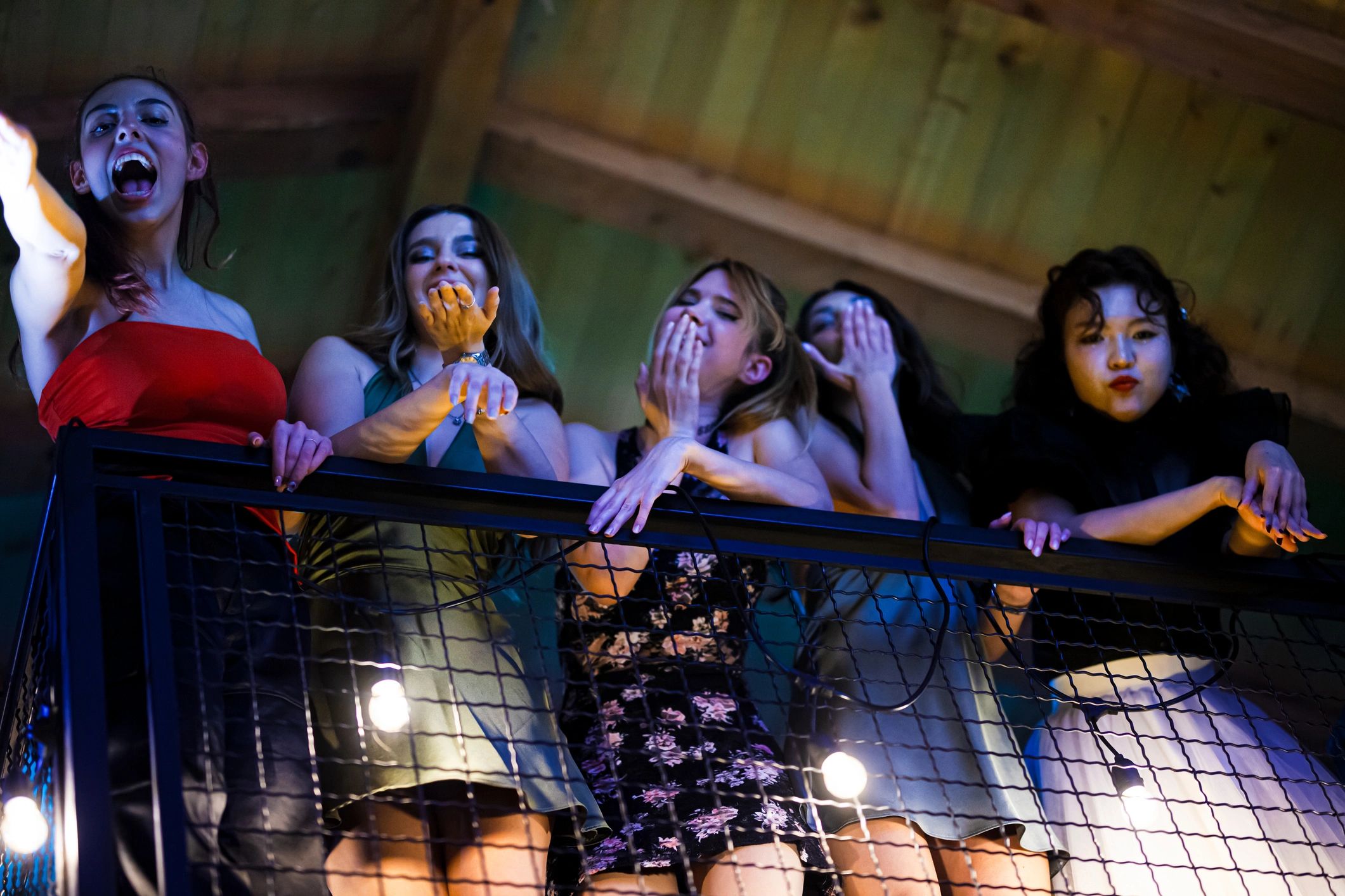 Friends celebrating on a balcony at night with colorful lights